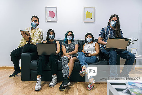 Gruppe junger Leute mit Masken während einer Pause in einem Coworking-Büro.