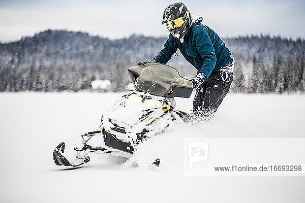 Confident and aggressive rider operates snowmobile in deep snow.