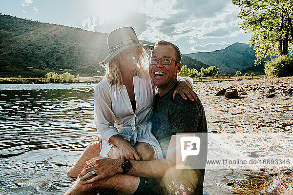 Porträt eines jungen Paares  das sich am Seeufer umarmt und lacht