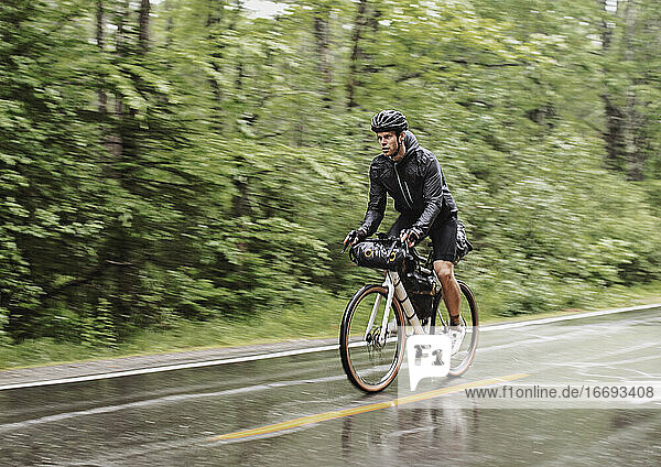 nasser und durchnässter Radfahrer fährt im strömenden Regen auf der Straße in Boothbay Maine