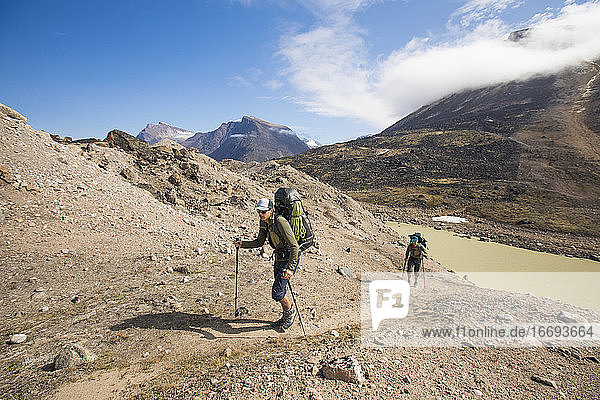 Rucksacktouristen wandern auf dem Akshayak-Pass auf Baffin Island einen Bergkamm hinauf.