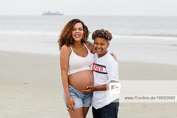Bruder posiert mit schwangerer Schwester am Strand