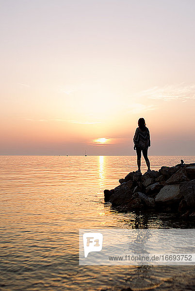 Frau Silhouette stehend auf Felsen am Meer