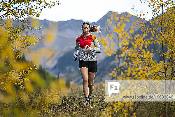 Young woman running in forest during autumn