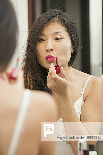 schöne Frau trägt Lippenstift auf  während sie in den Spiegel schaut