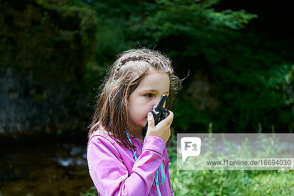 Beautiful Young Girl Using A Walkie-Talkie On Forest