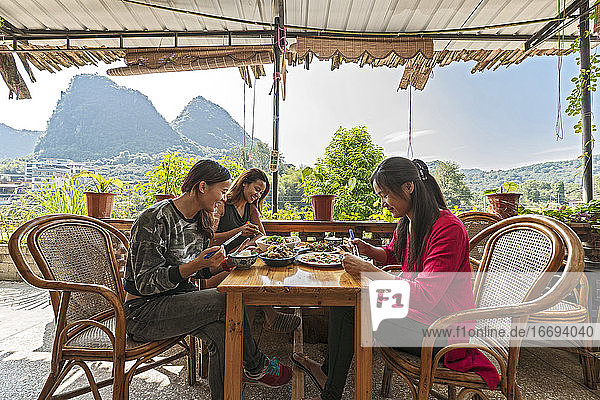 drei Freundinnen beim Mittagessen auf der Terrasse