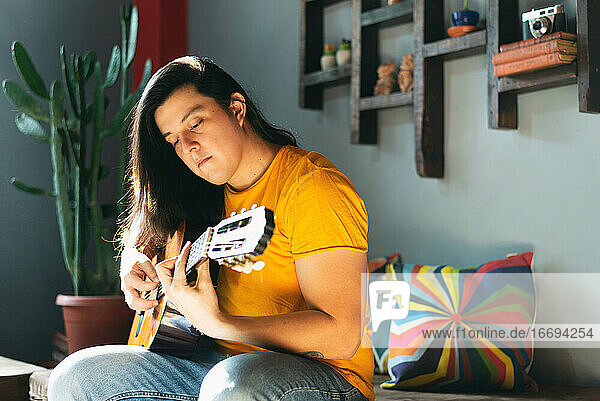 Seitenansicht  Mann mit langen Haaren spielt Akustikgitarre  entspannte Haltung