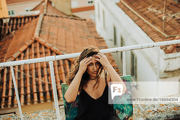Traurige oder depressive Frau auf dem Dach sitzend mit Blick auf die Dachterrasse