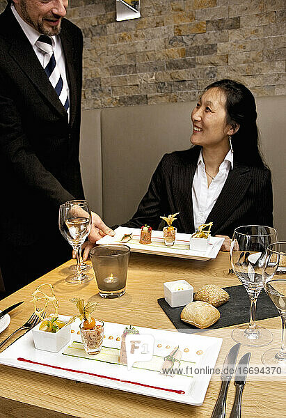 Kellner überreicht Vorspeise an Geschäftsfrau in Luxusrestaurant