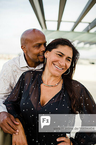 Multirassisches Paar in den späten Vierzigern  das sich bei Sonnenuntergang in San Diego umarmt