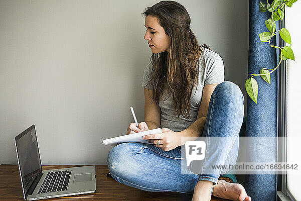Einzelne Frau an ihrem Laptop bei der Arbeit / beim Lernen zu Hause