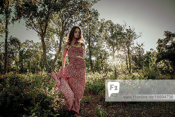 Junge Frau in langem Sommerkleid mitten im Wald
