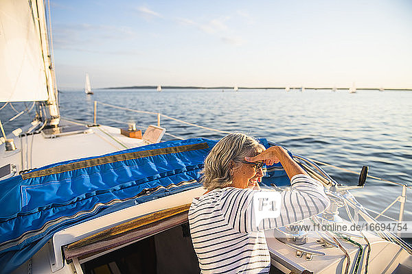 Frau mittleren Alters genießt den Sommer beim Segeln während der goldenen Stunde