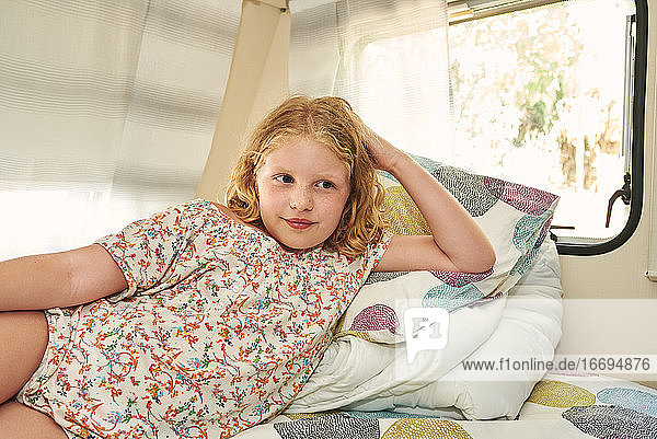 Ein Mädchen liegt in einem Wohnwagen. Sie ist entspannt in ihrem Urlaub.