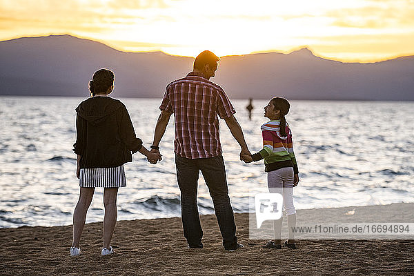 Ein Vater und seine Töchter beobachten den Sonnenuntergang am Strand von Lake Tahoe  NV