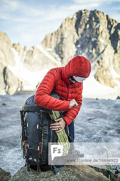Bergsteiger packt seinen Rucksack in einer Berglandschaft.