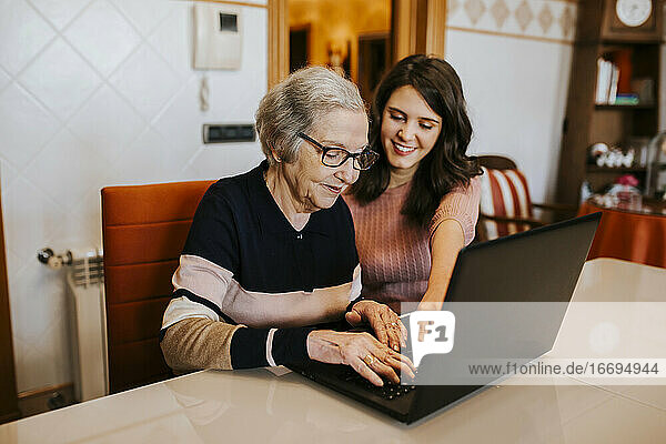 Enkelin bringt ihrer Großmutter etwas auf dem Laptop bei