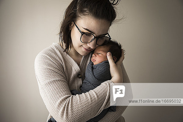 Modern Millennial Hipster Mom Snuggles Swaddled Newborn Baby Sohn