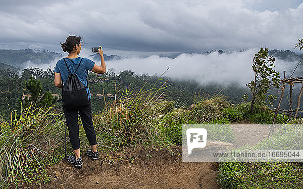 Frau beim Fotografieren auf dem Gipfel des Adam's Peak in der Nähe von Ella