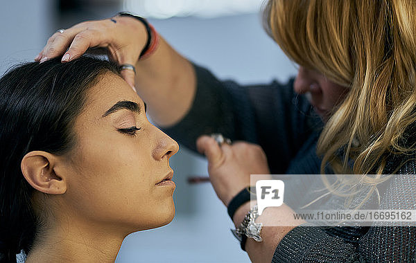Close-up of a make-up artist touching up a model's face