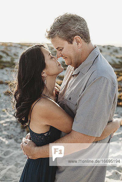 Mid-40's man and woman with closed eyes embracing and touching noses
