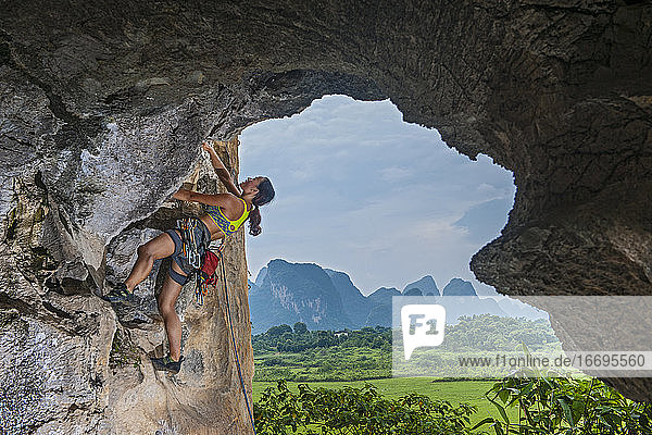 junge Bergsteigerin beim Klettern in einem abgelegenen Gebiet in Yangshuo  China
