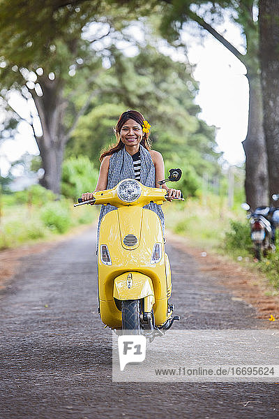 Vietnamesische Frau mit gelbem Motorroller in einer ländlichen Gegend in Vietnam