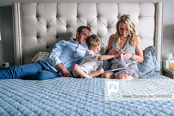 family relaxing and reading a book on a bed in the afternoon