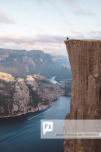 Mann sitzt am Rande einer Klippe am Preikestolen  Norwegen