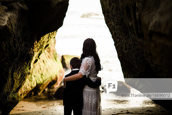 Mutter und Sohn umarmen sich mit Blick auf das Meer am Strand von San Diego