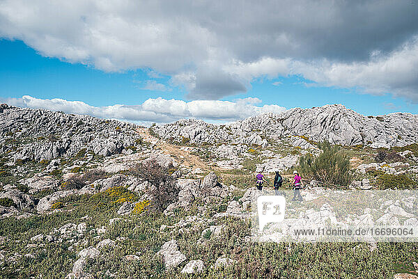 Konzept: Abenteuer. Drei Bergsteiger mit Helm und Klettergurt. Sie wandern in der Ebene auf dem Gipfel des Berges. Kalksteinfelsenlandschaft und niedrige Vegetation. Andalusien  Spanien.