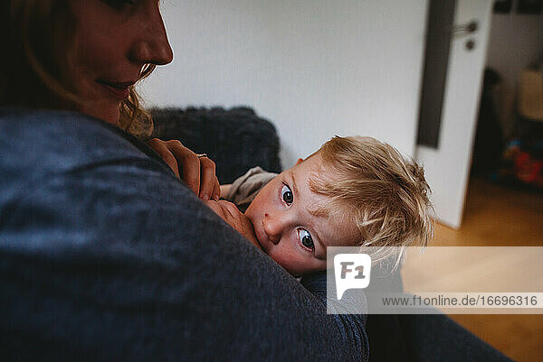 Young boy breastfeeding at home snuggled up with his mom