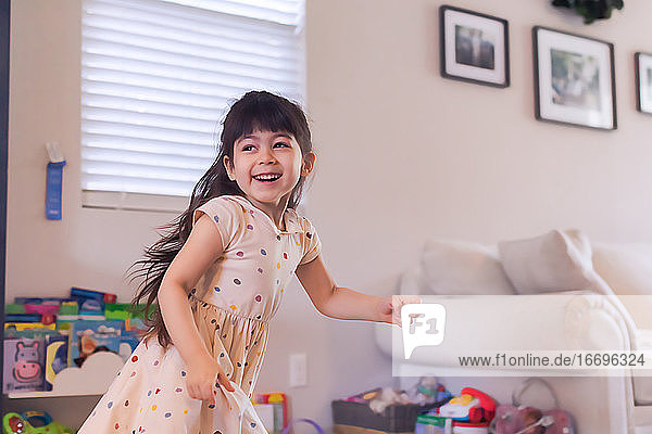 Girl in polka dot dress running in the living room.