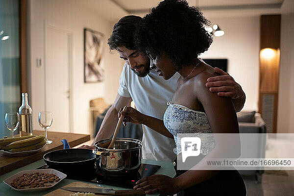 Multiethnic couple cooking romantic dinner together