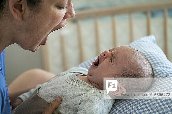 Mutter mit offenem Mund imitiert gähnendes Baby zu Hause
