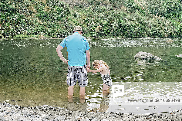 Father and daughter at a scenic river spot playing in the water
