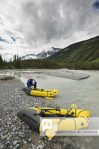 Adventurous man inflating packrafts in the rocky mountains.