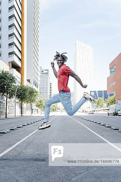 Aufgeregter ethnischer Mann springt auf der Straße