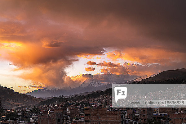 Große orangefarbene Wolken bei Sonnenuntergang über Huaraz und der Cordillera Blanca