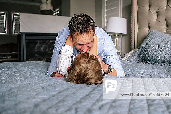 Glücklicher Vater und Sohn spielen auf dem Bett