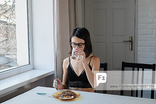 Junge Frau in Unterwäsche beim Frühstück am Tisch