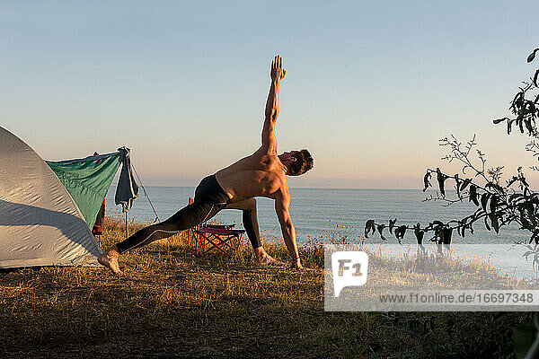 Erwachsener Mann macht körperliche Übungen bei Sonnenaufgang  vor dem Te
