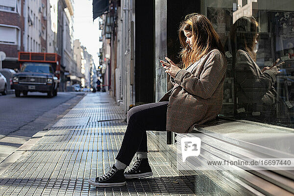 Teenager-Mädchen mit einem Smartphone auf einer Straße in Buenos Aires