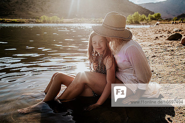 Mutter und Tochter umarmen sich und haben einen ruhigen Moment am Seeufer