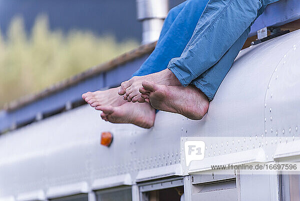 Seitenansicht von nackten Füßen  die vom Dach des Schulbusses hängen zwei Personen