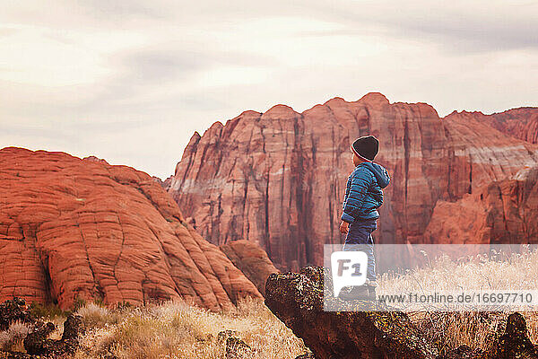 Little boy by the red sandstone cliffs and mountains in Utah