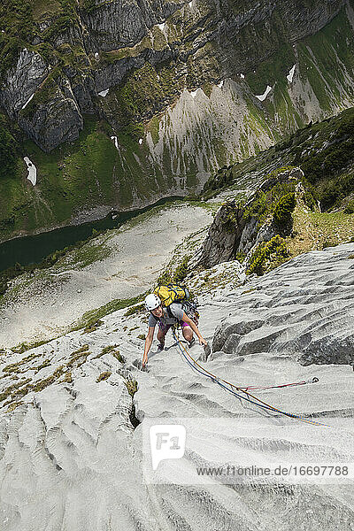 Woman rock climbs limestone cliff in Alpstein  Appenzell  Switzerland