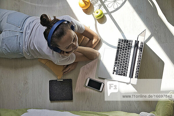 Junge Frau am Fenster liegend zu Hause mit Laptop