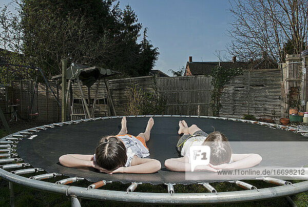 zwei junge Mädchen entspannen sich auf einem Trampolin in Woking - England